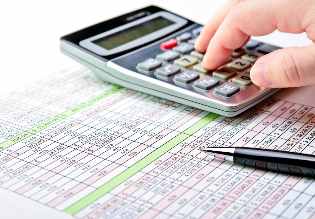 A person using a calculator to analyze financial data for tax filing