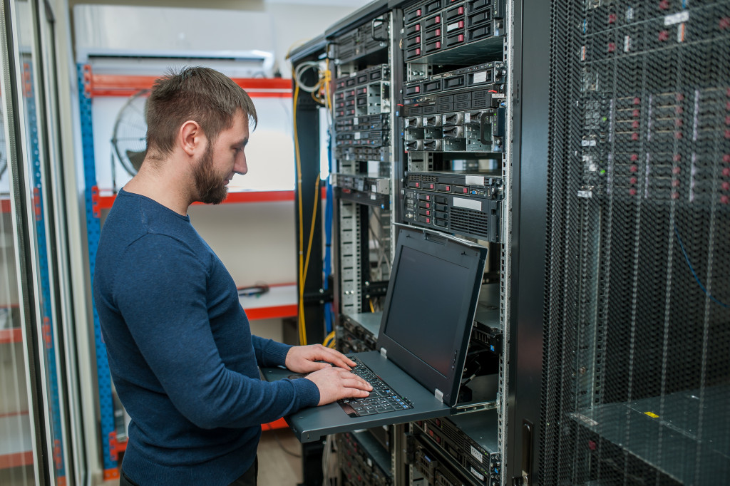 IT employee using laptop in server room