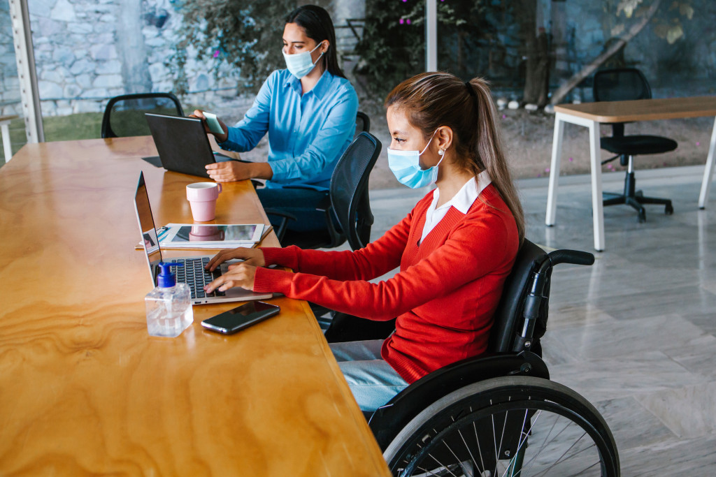 young woman in wheelchair working while wearing a mask