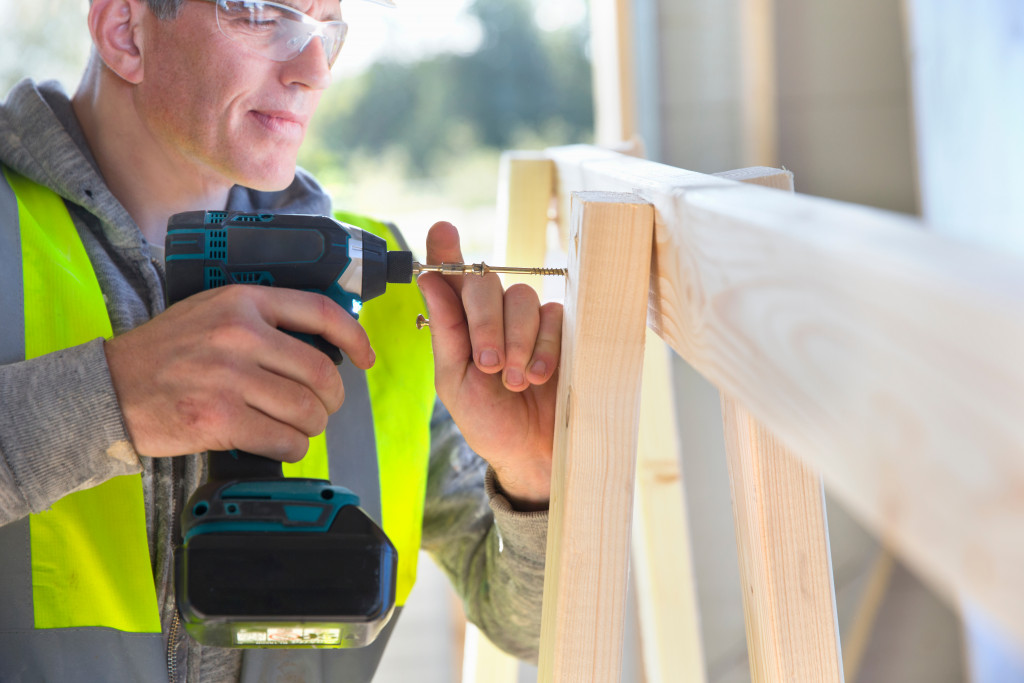 A male construction worker using a portable drill