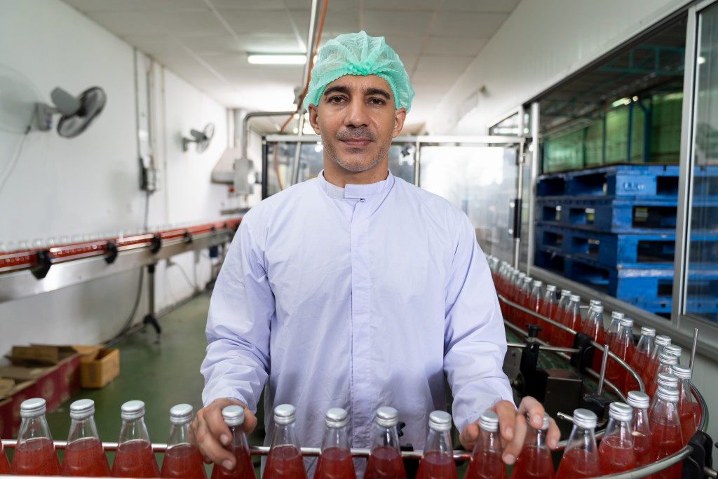 a man holding bottles filled with liquid in a production line
