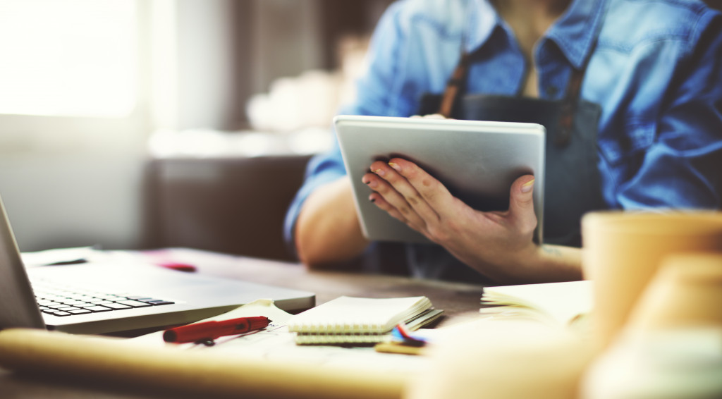 woman using tablet to fulfill documents instead of using papers in her office table