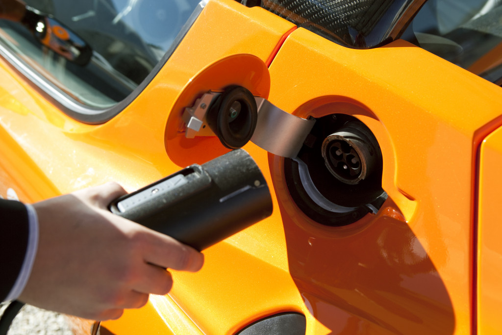 hand charging orange electrical car