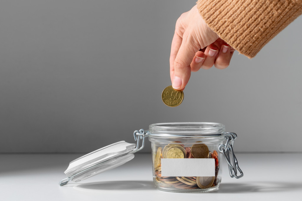 person adding coins to a glass jar